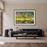 Bournda Lagoon's Serenity framed print in black with a white mat, above a navy linen sofa in a lounge room