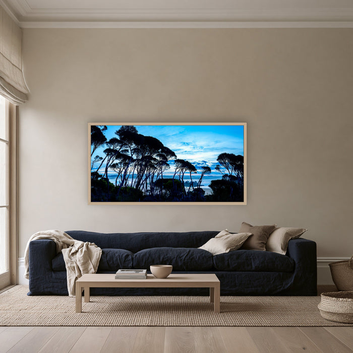 Wallagoot Lake and Sea at Blue Hour framed print in oak without a mat, above a navy linen sofa in a lounge room